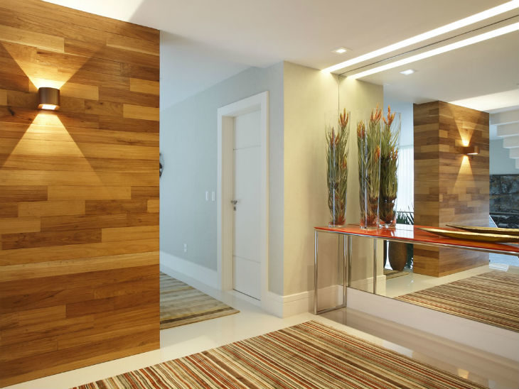 Hall de entrada elegante com espelho grande refletindo a luz e ampliando o espaço.